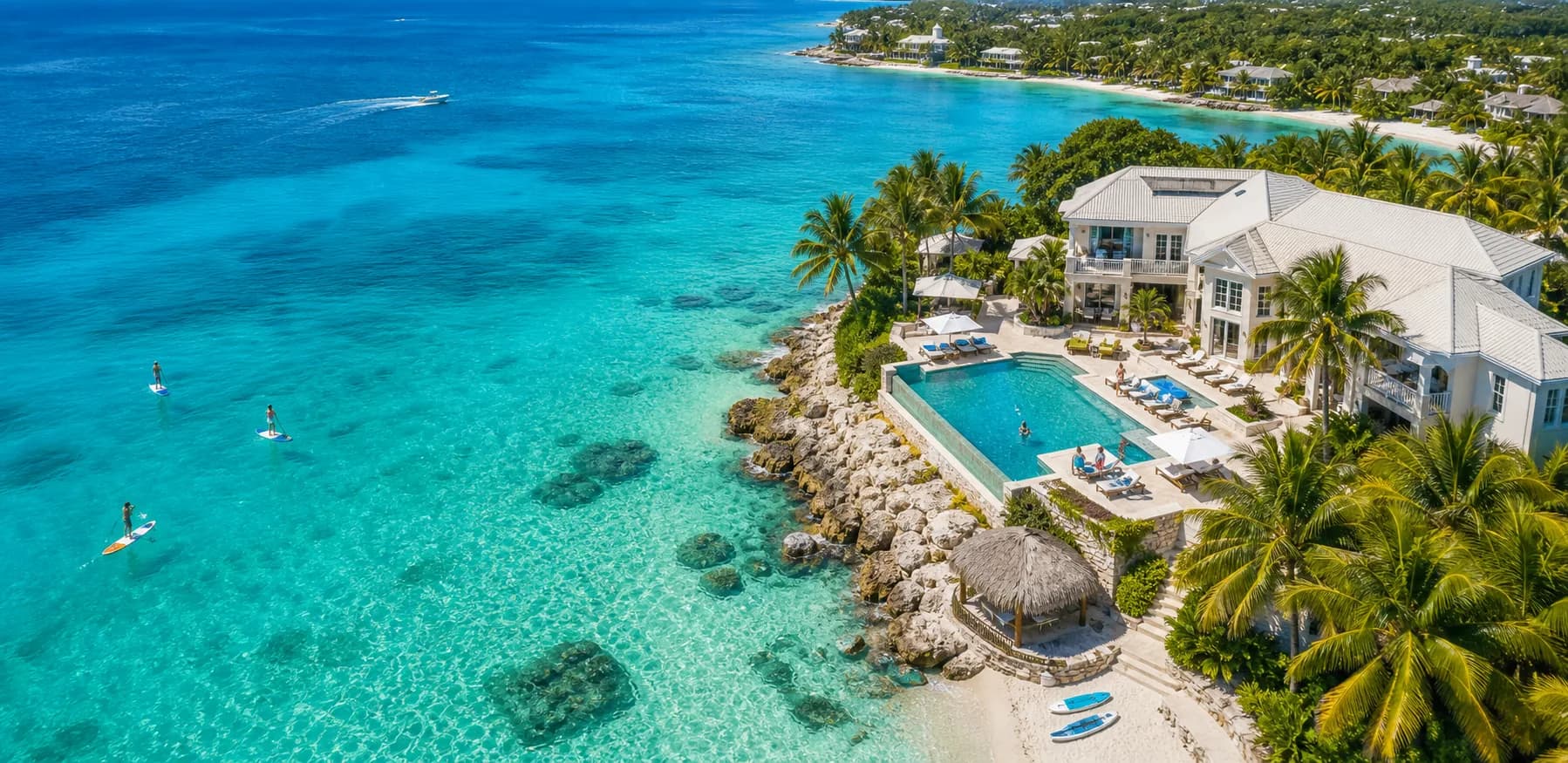 Aerial Cayman vacation villa with pool beside turquoise sea